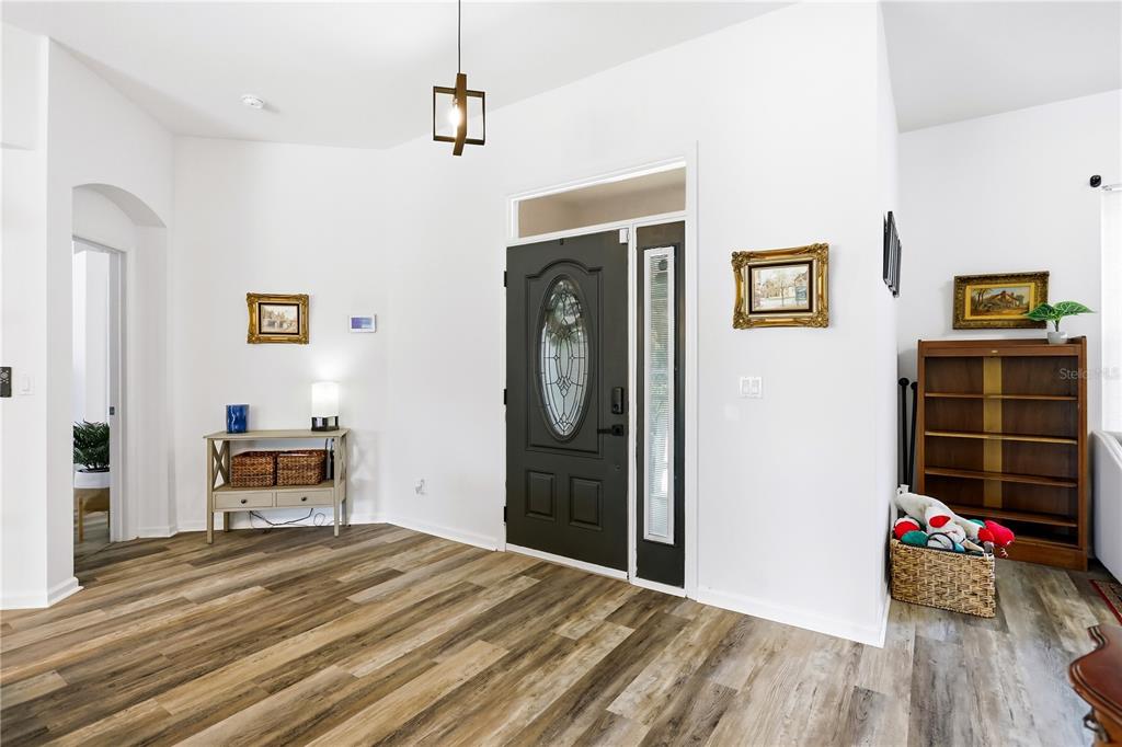 An entryway features wood-look flooring, a dark front door with a glass insert, and furniture — 13706 VIA ROMA CIRCLE, CLERMONT, FL