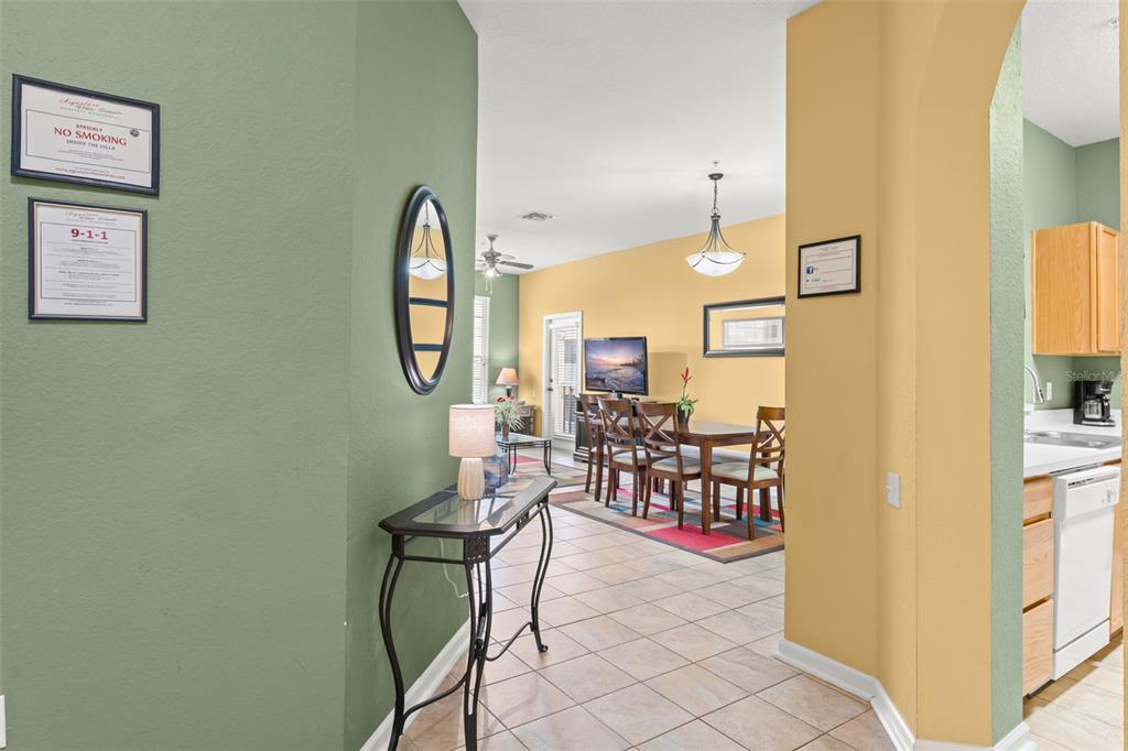 A hallway with a console table leads into a dining area and kitchen — 7675 COMROW STREET UNIT 405, KISSIMMEE, FL