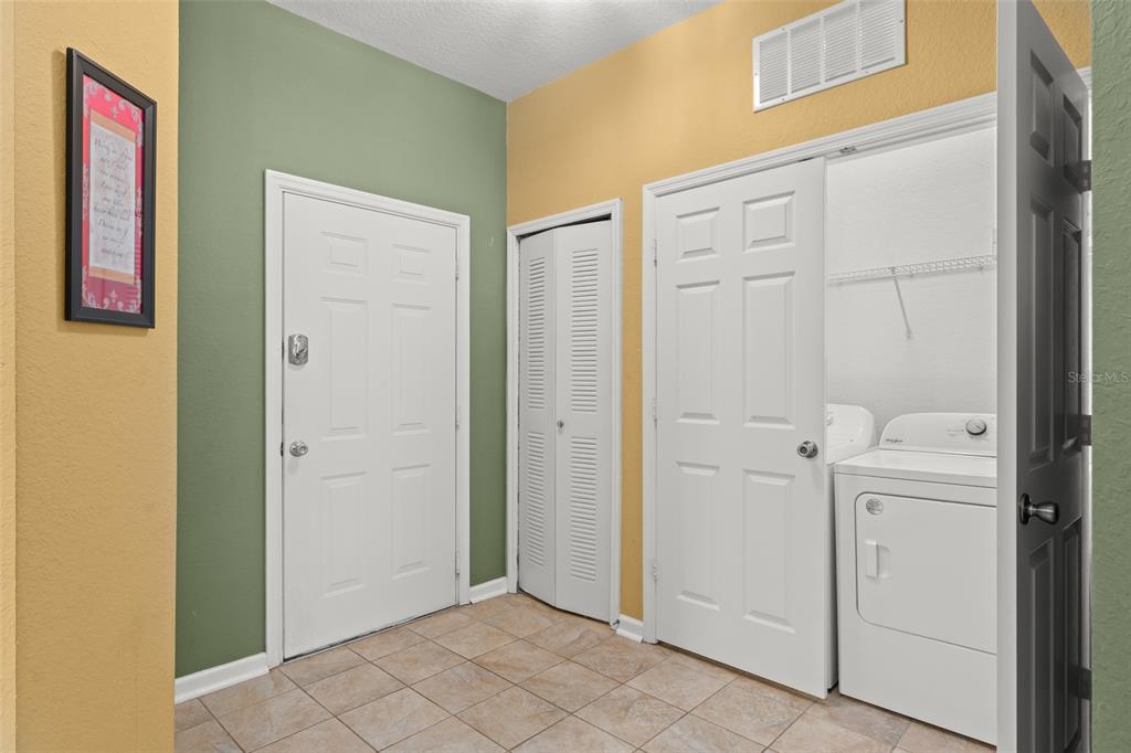 A laundry room with tile flooring, a white door, a closet, and a washer-dryer set — 7675 COMROW STREET UNIT 405, KISSIMMEE, FL