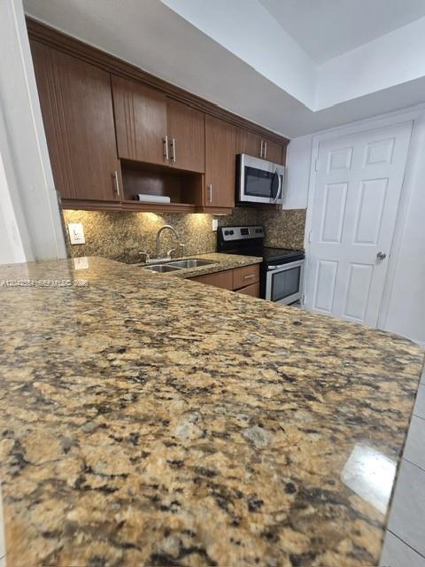 A kitchen features wood cabinets, granite countertops, a stainless steel microwave, and a white door — 2441 NW 13th St # 62, Miami FL 33125, MIAMI, FL