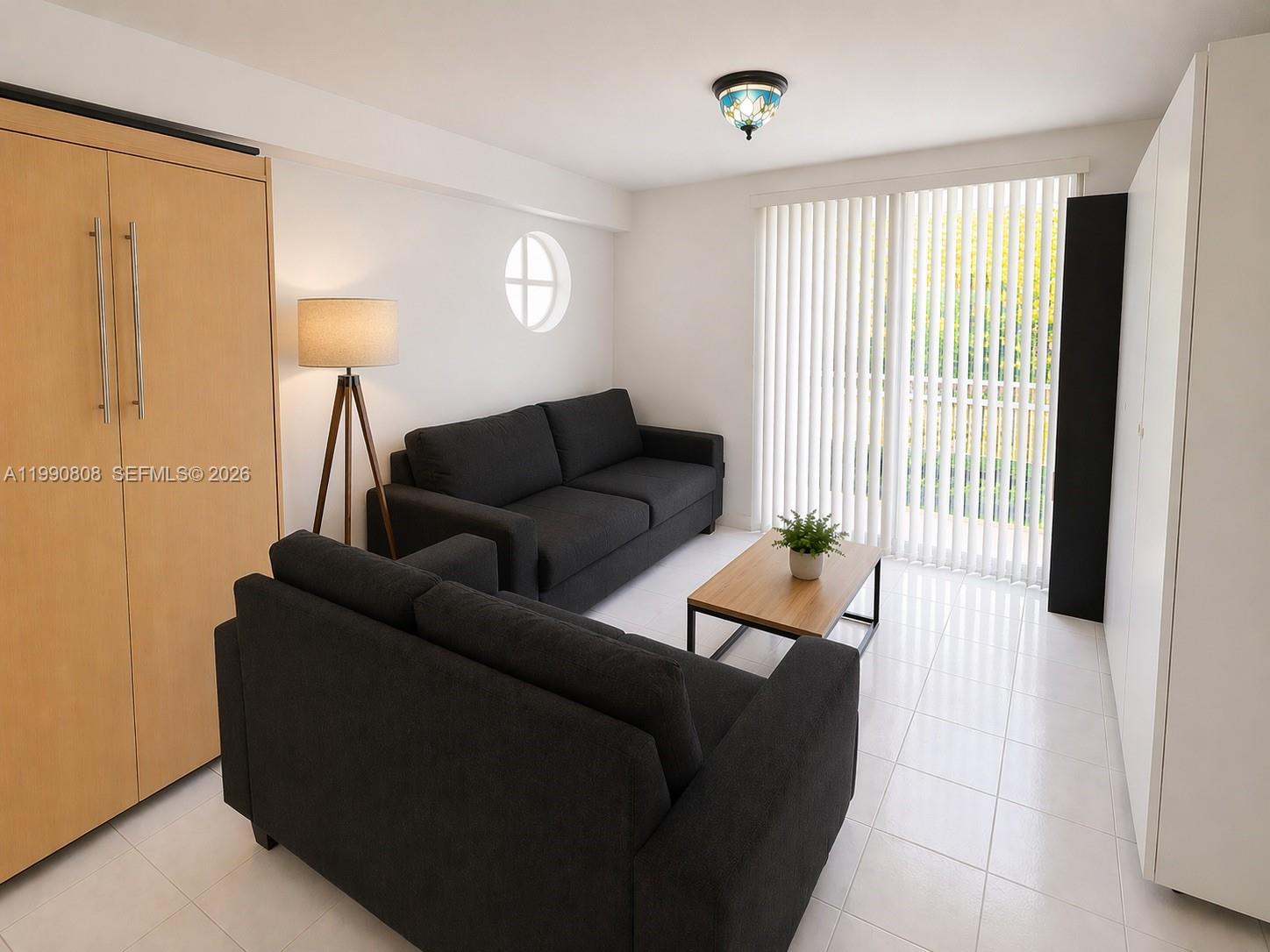 A living room features two dark sofas, a wooden coffee table, and white tile flooring — 9156 Collins Ave # 107, Surfside FL 33154, SURFSIDE, FL
