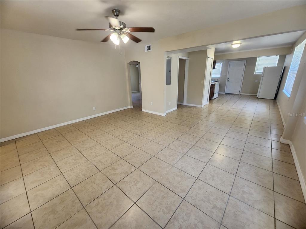 An open-concept living area features light-colored floor tiles, beige walls, and a ceiling fan — 343 W 60TH STREET, JACKSONVILLE, FL