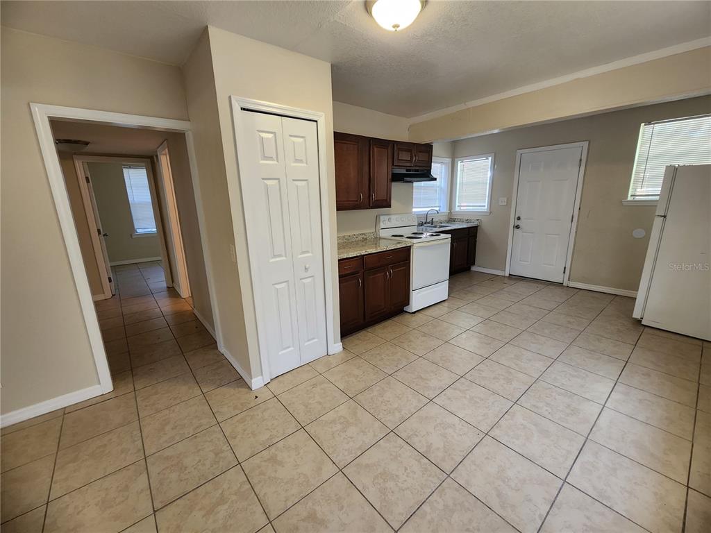 A kitchen with dark wood cabinets, tile flooring, and a white stove and refrigerator — 343 W 60TH STREET, JACKSONVILLE, FL