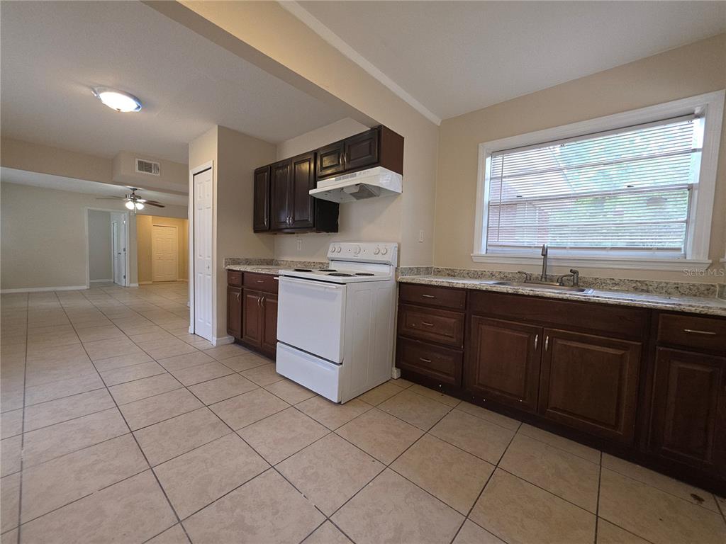 A kitchen features dark wood cabinets, granite countertops, a white stove, and beige tile flooring — 343 W 60TH STREET, JACKSONVILLE, FL