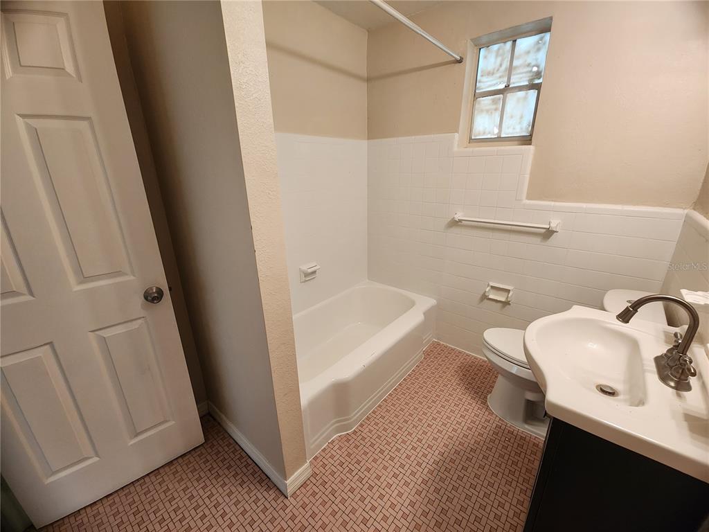 A bathroom features a white bathtub, a pedestal sink, a toilet, and patterned tile flooring — 343 W 60TH STREET, JACKSONVILLE, FL
