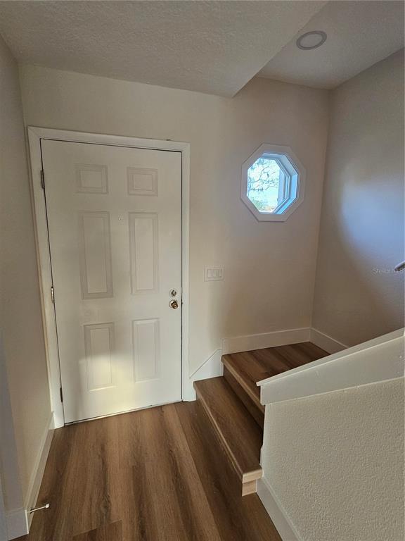 An entryway features a white door, wood-look flooring, and a small octagonal window above stairs — 11730 WHITEWING COURT, ORLANDO, FL