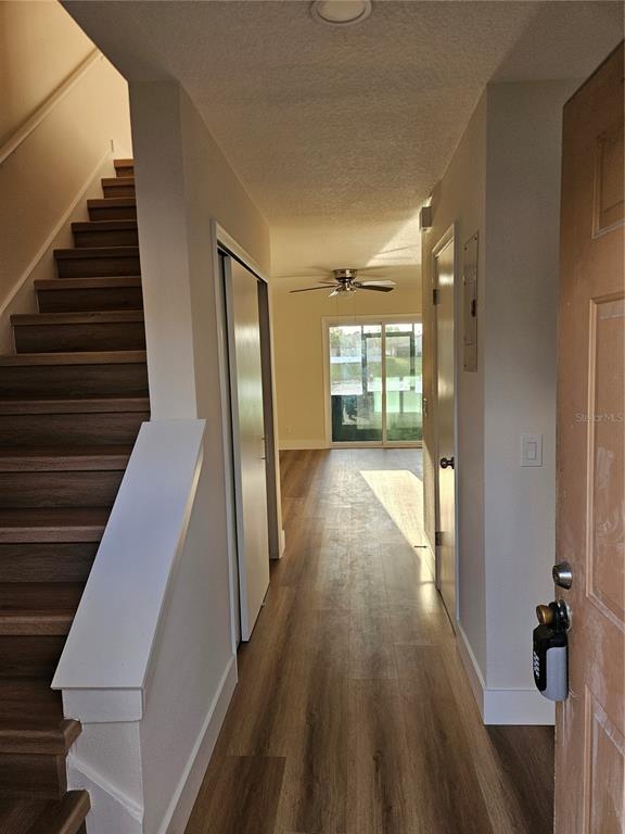 An entryway with wood-look flooring leads to a living area with a sliding glass door — 11730 WHITEWING COURT, ORLANDO, FL