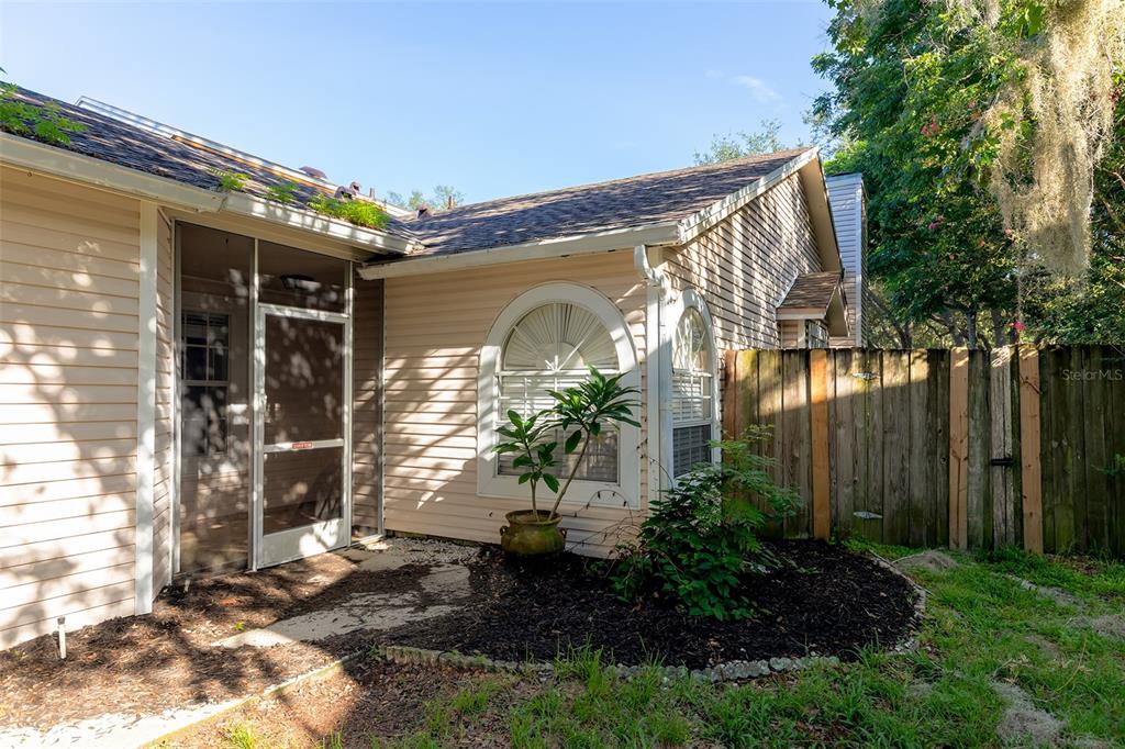 The exterior of a house features beige siding, a screened porch, and a wooden fence — 824 HILLARY COURT, LONGWOOD, FL