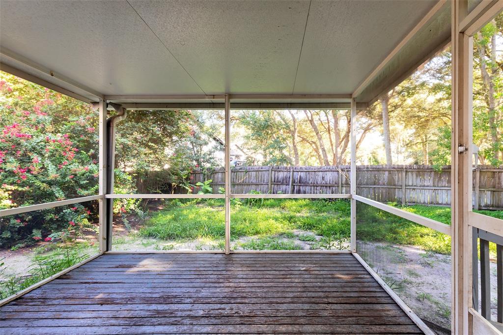 A screened-in porch features a wooden deck and a view of a fenced backyard — 824 HILLARY COURT, LONGWOOD, FL