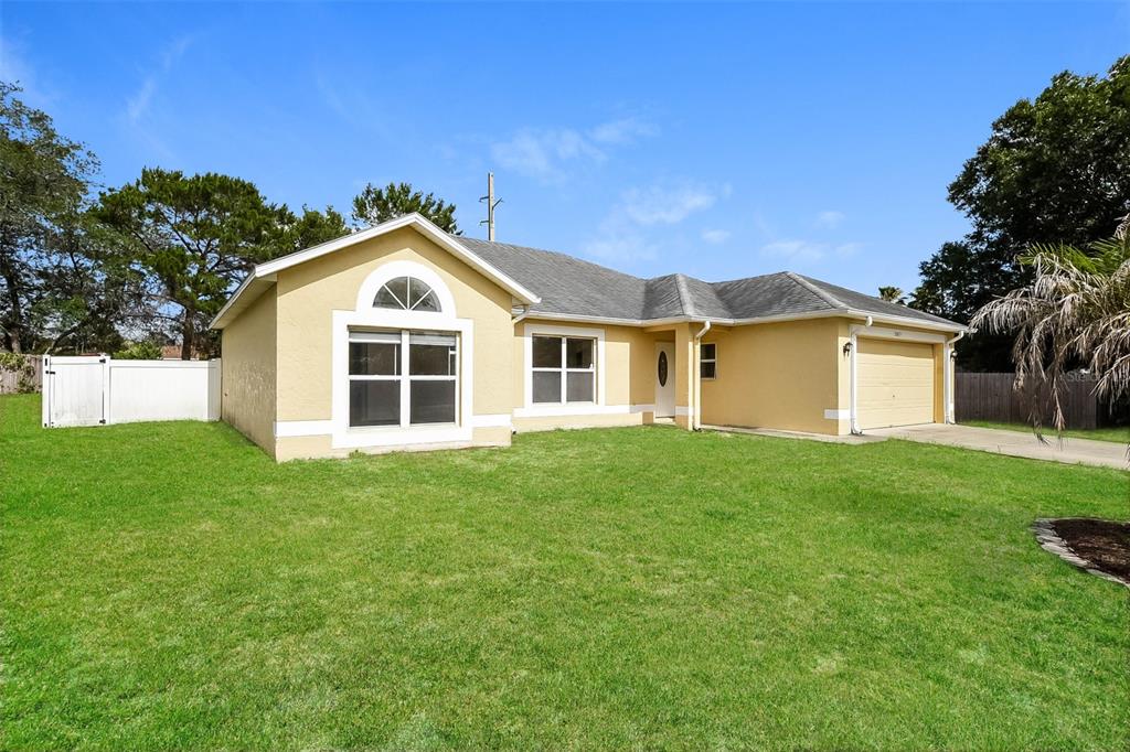 A single-story yellow house with a two-car garage and a large front lawn — 2807 ARBOUR TRAIL COURT, DELTONA, FL