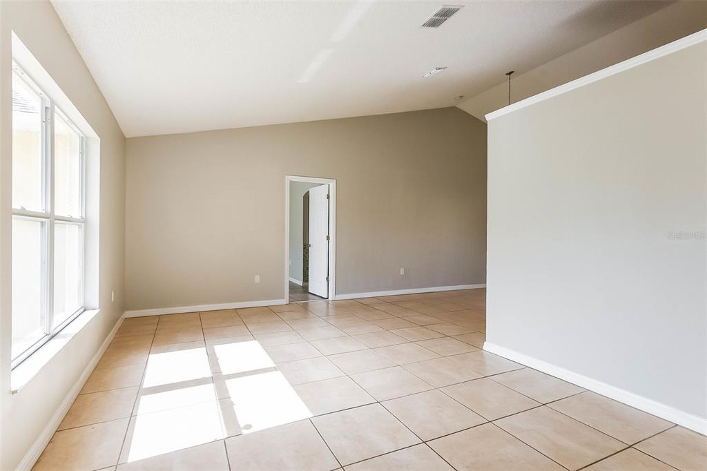 A room with beige walls, tile flooring, a vaulted ceiling, and a doorway — 2807 ARBOUR TRAIL COURT, DELTONA, FL