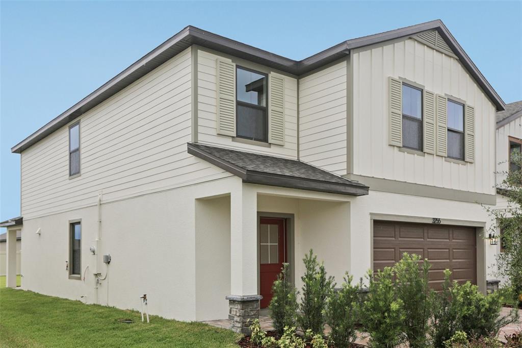 A two-story house with beige siding, a red front door, and a brown garage door — 3255 CUP DRIVE, LAKELAND, FL