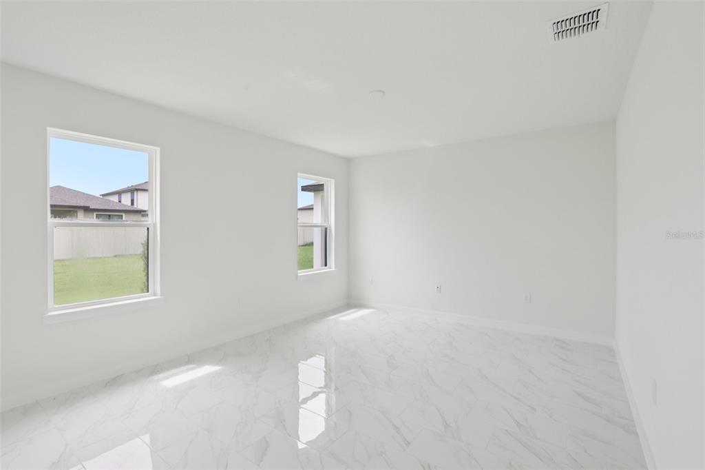 An empty bedroom features white walls, two windows, and glossy white marble-patterned tile flooring — 3255 CUP DRIVE, LAKELAND, FL
