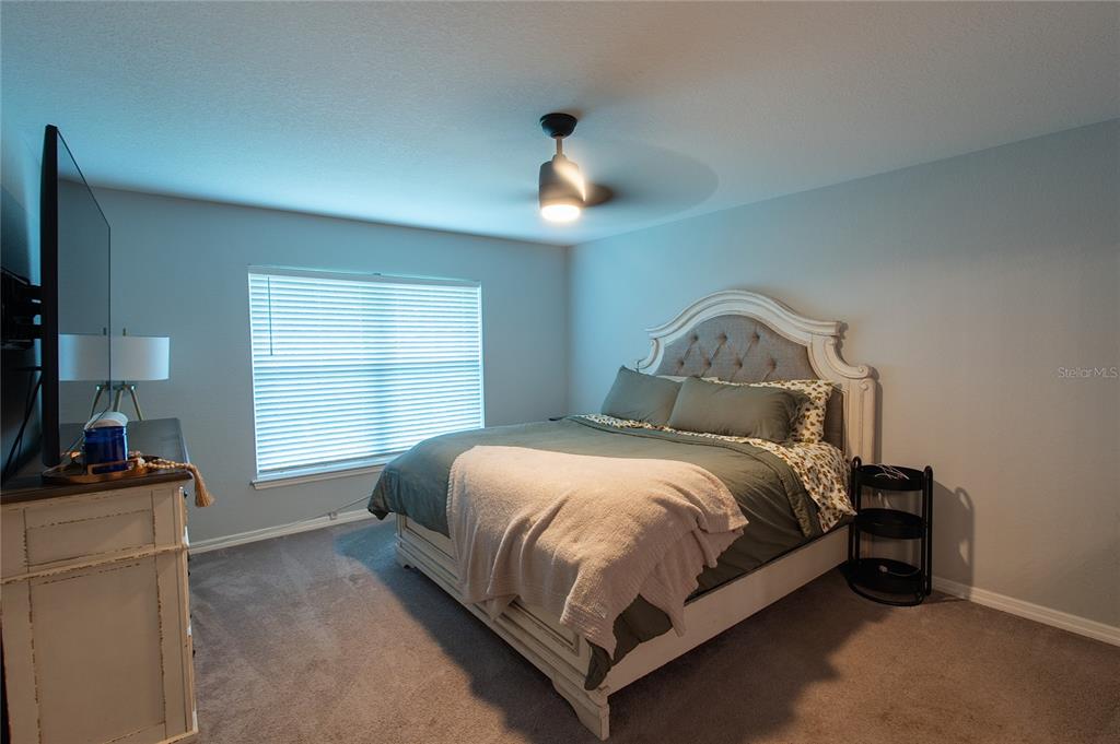 A bedroom features a tufted headboard bed, a ceiling fan, and a dresser with a television — 3715 TEAKWOOD STREET, FORT MYERS, FL