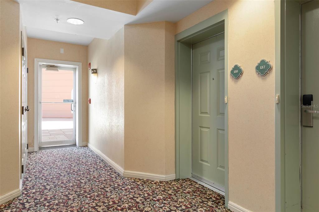 A carpeted hallway features two doors with unit numbers and a glass exterior door — 200 OCEAN CREST DRIVE UNIT 138, PALM COAST, FL
