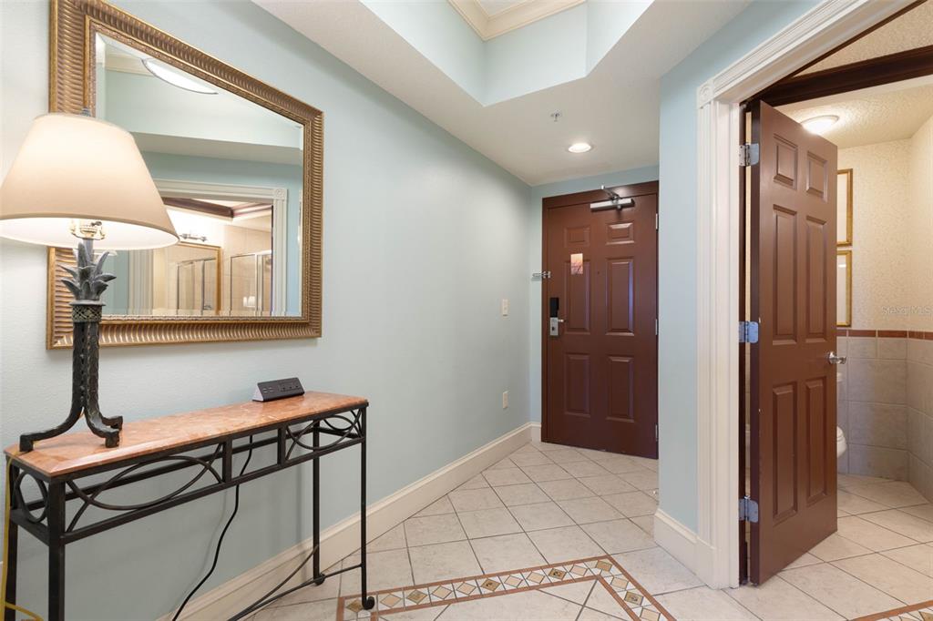 An entryway features a console table, a lamp, a mirror, and a tiled floor — 200 OCEAN CREST DRIVE UNIT 138, PALM COAST, FL