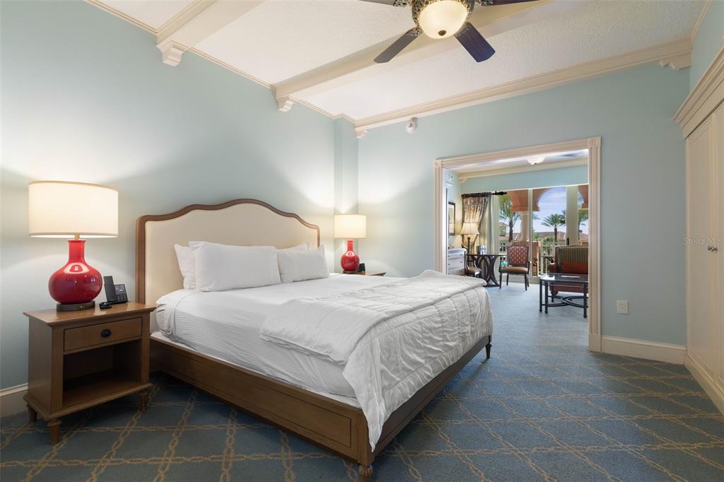 A bedroom with a king bed, light blue walls, patterned carpet, and an adjoining balcony — 200 OCEAN CREST DRIVE UNIT 138, PALM COAST, FL