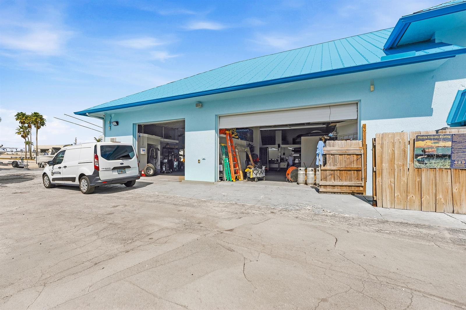 A light blue commercial building features two open garage bays and a white cargo van — 250 SW Monterey Road, Stuart FL 34994, STUART, FL