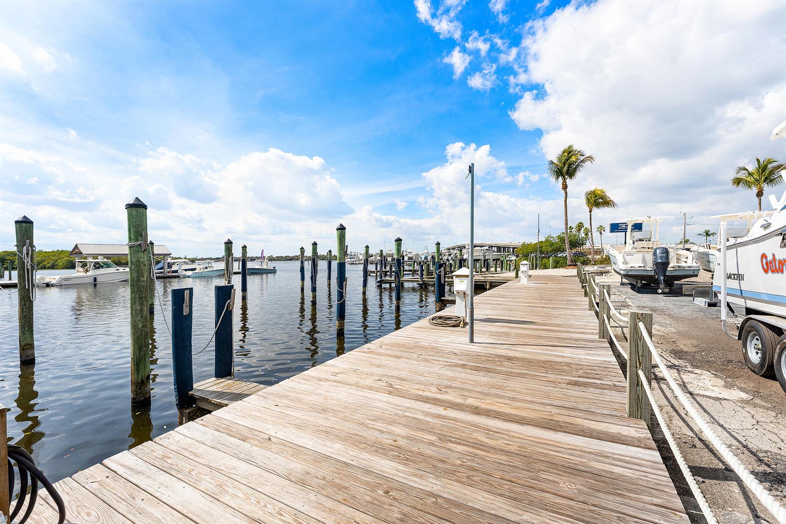 A wooden dock extends into a marina with several boats moored to pilings — 250 SW Monterey Road, Stuart FL 34994, STUART, FL