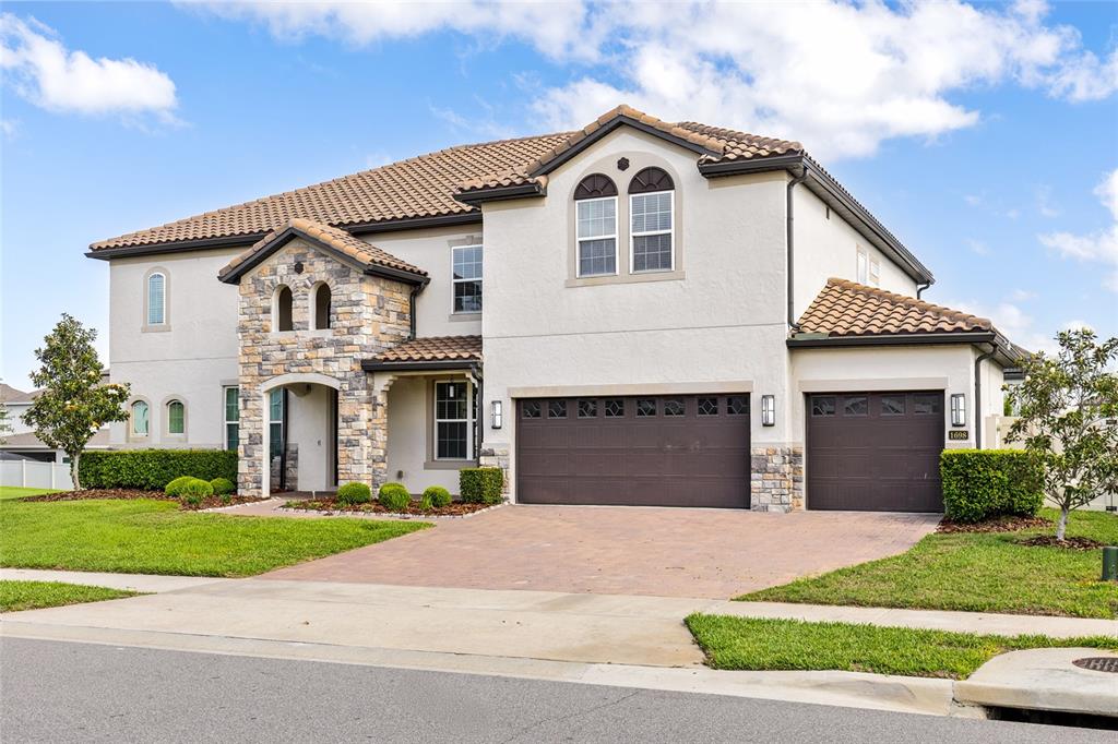 A two-story house with a stone facade, tile roof, and a three-car garage — 1698 JUNIPER HAMMOCK STREET, WINTER GARDEN, FL