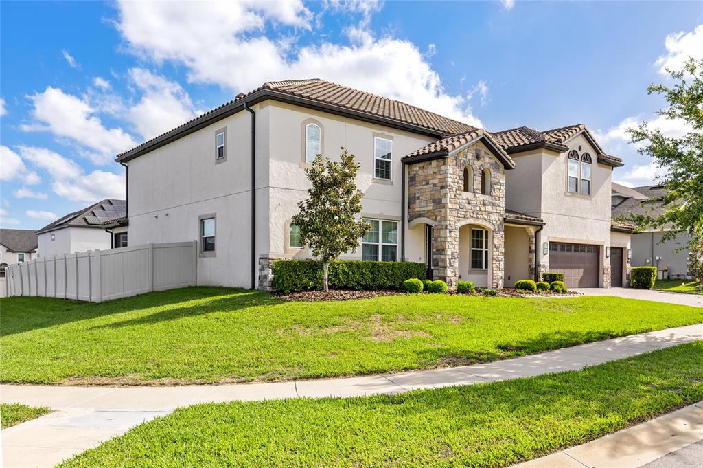 A two-story house with a stone facade, stucco exterior, and a tiled roof — 1698 JUNIPER HAMMOCK STREET, WINTER GARDEN, FL