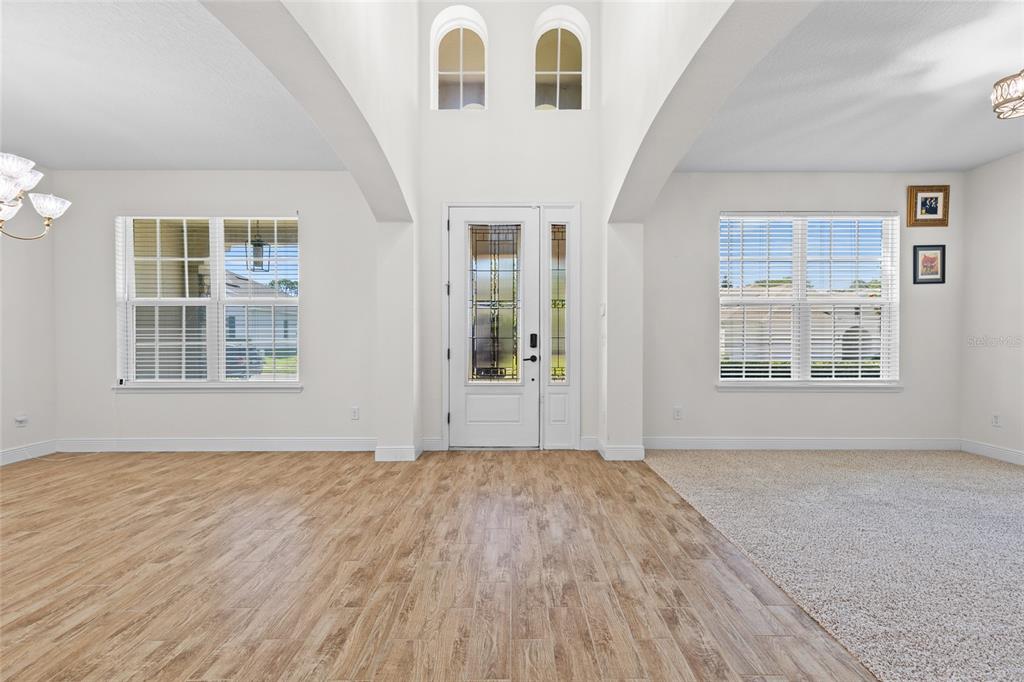 A bright entryway features a high ceiling, wood-look tile flooring, and a glass-paneled front door — 1698 JUNIPER HAMMOCK STREET, WINTER GARDEN, FL