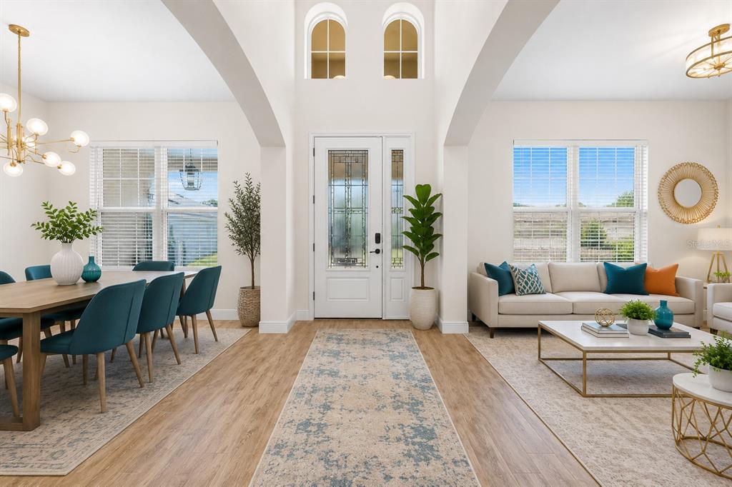 A bright, open-concept living and dining area features white walls, vaulted ceilings, and wood flooring — 1698 JUNIPER HAMMOCK STREET, WINTER GARDEN, FL
