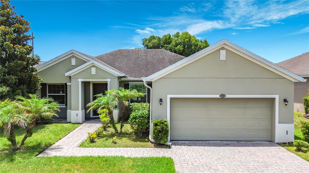 A single-story house with a two-car garage, light green stucco exterior, and a paved walkway — 4834 TERRA SOLE PLACE, ST CLOUD, FL