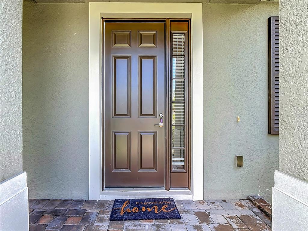 A brown front door with a side window sits on a paved porch — 4834 TERRA SOLE PLACE, ST CLOUD, FL