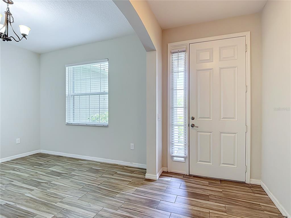 An entryway with wood-look tile flooring leads into a dining area with a window — 4834 TERRA SOLE PLACE, ST CLOUD, FL