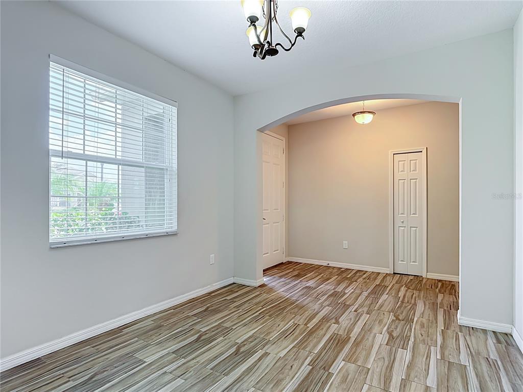 A room with wood-look tile flooring, an arched entryway, and a window with blinds — 4834 TERRA SOLE PLACE, ST CLOUD, FL