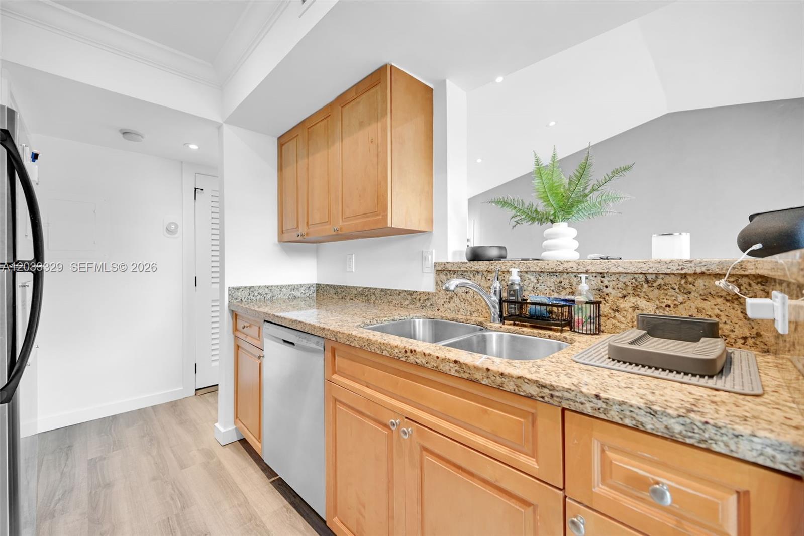 A kitchen features light wood cabinets, granite countertops, a stainless steel dishwasher, and a sink — 10560 SW 156th Pl # 208, Miami FL 33196, MIAMI, FL
