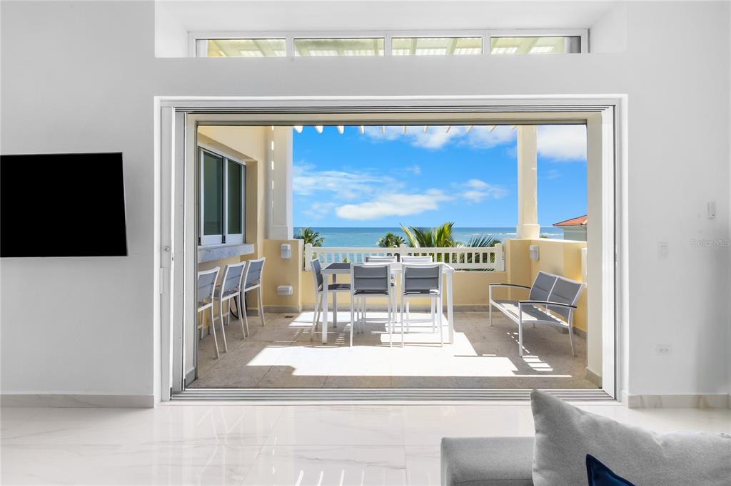 A bright living room opens through large sliding glass doors to a furnished oceanfront balcony — 400 OCEAN DRIVE UNIT 453, HUMACAO, PR