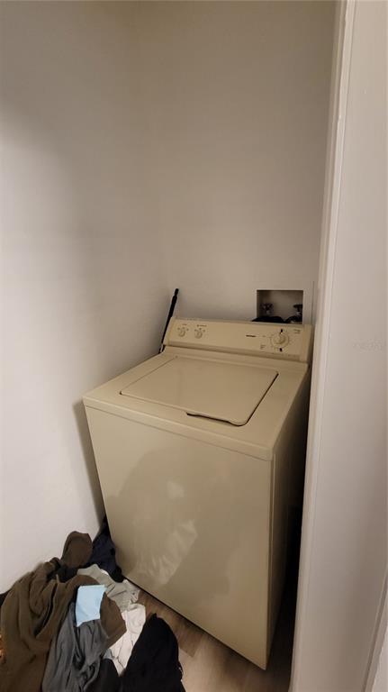 A top-loading washing machine sits in a small laundry closet with white walls — 4400 THORNBRIAR LANE UNIT 201, ORLANDO, FL