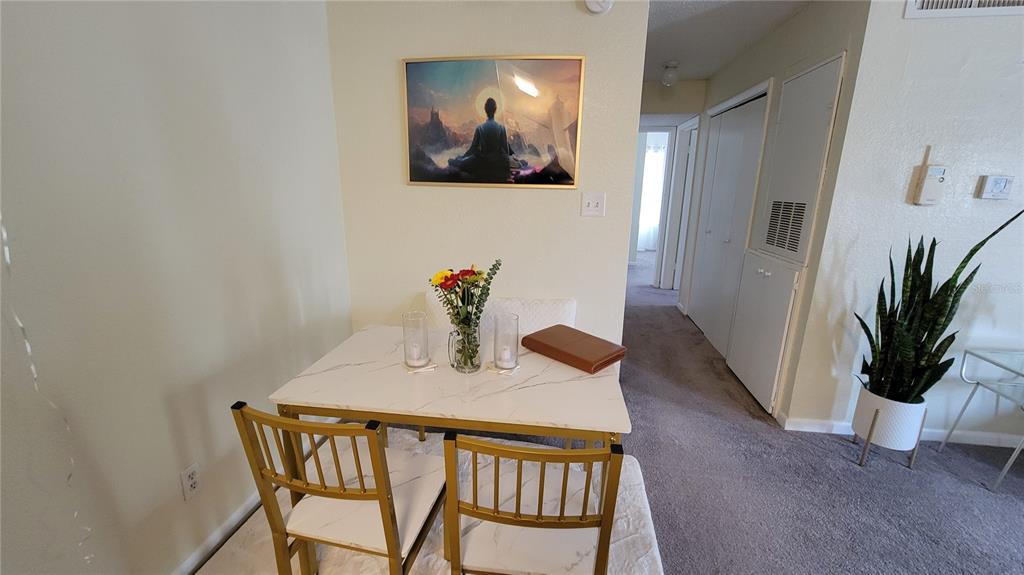 A dining area features a marble-topped table with gold chairs beneath a framed wall print — 4400 THORNBRIAR LANE UNIT 201, ORLANDO, FL