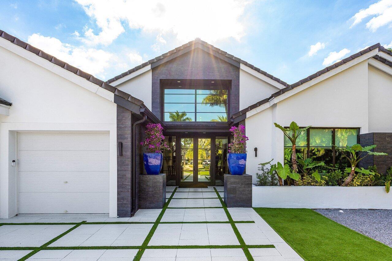 The exterior of a modern house features a white facade, dark stone accents, and glass doors — 3746 NW 53rd Street, Boca Raton FL 33496, BOCA RATON, FL