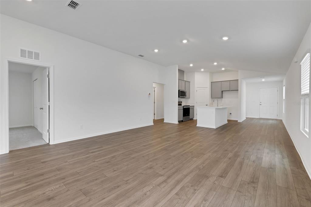 An open-concept living area features wood-look flooring, recessed lighting, and a kitchen with gray cabinets — 5704 LAGOON CRUISE WAY, JACKSONVILLE, FL