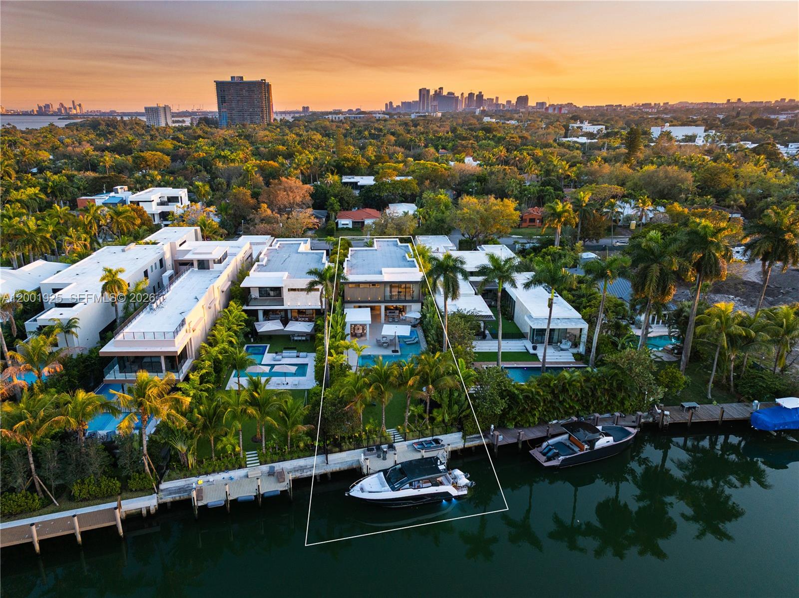 An aerial view shows a modern waterfront house with a pool and a docked boat — 707 NE 77th St, Miami FL 33138, MIAMI, FL
