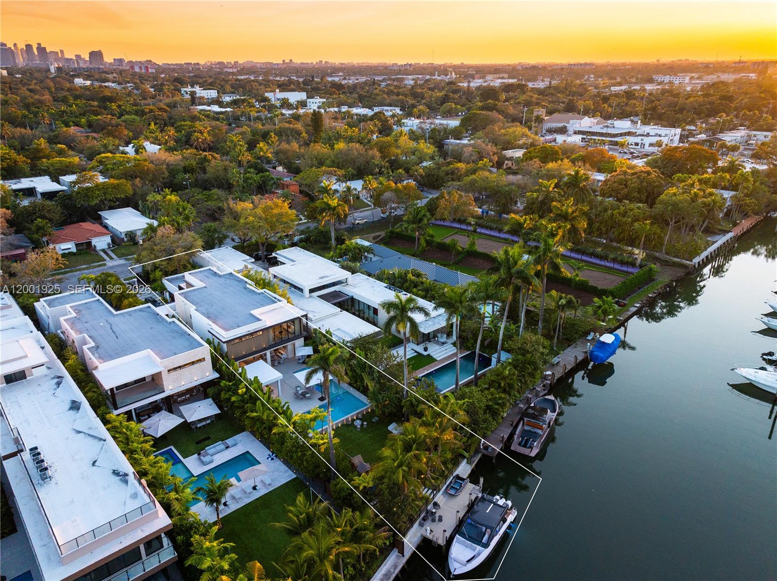 An aerial view shows a modern waterfront home with a pool, dock, and boat — 707 NE 77th St, Miami FL 33138, MIAMI, FL