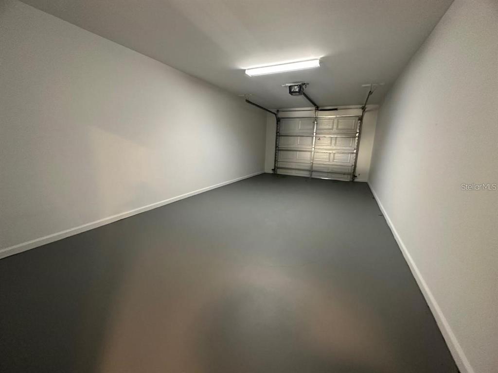 An empty garage with a gray painted floor, white walls, and a metal door — 12220 WILD IRIS WAY UNIT 108, ORLANDO, FL