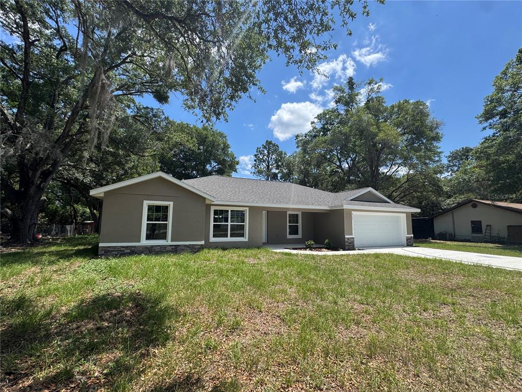 A single-story house with a tan exterior, stone accents, and a two-car garage — 8121 SW 202ND TERRACE, DUNNELLON, FL