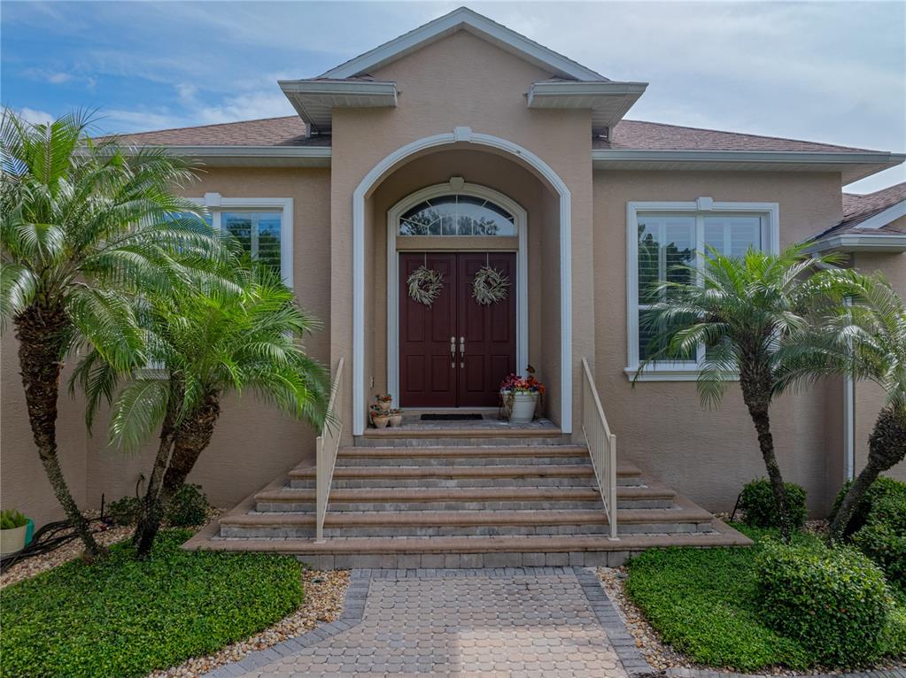 The exterior of a tan house features a brick walkway leading to double front doors — 11972 W RIVERHAVEN DRIVE, HOMOSASSA, FL