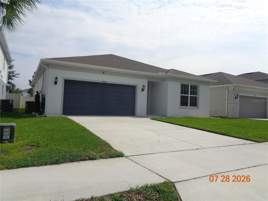 A single-story house with a gray garage door, light-colored stucco walls, and a concrete driveway — 2023 CANOPY TERRACE BOULEVARD, DELAND, FL
