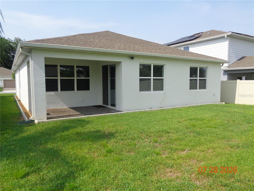The exterior of a white stucco house features a covered patio and a grassy backyard — 2023 CANOPY TERRACE BOULEVARD, DELAND, FL