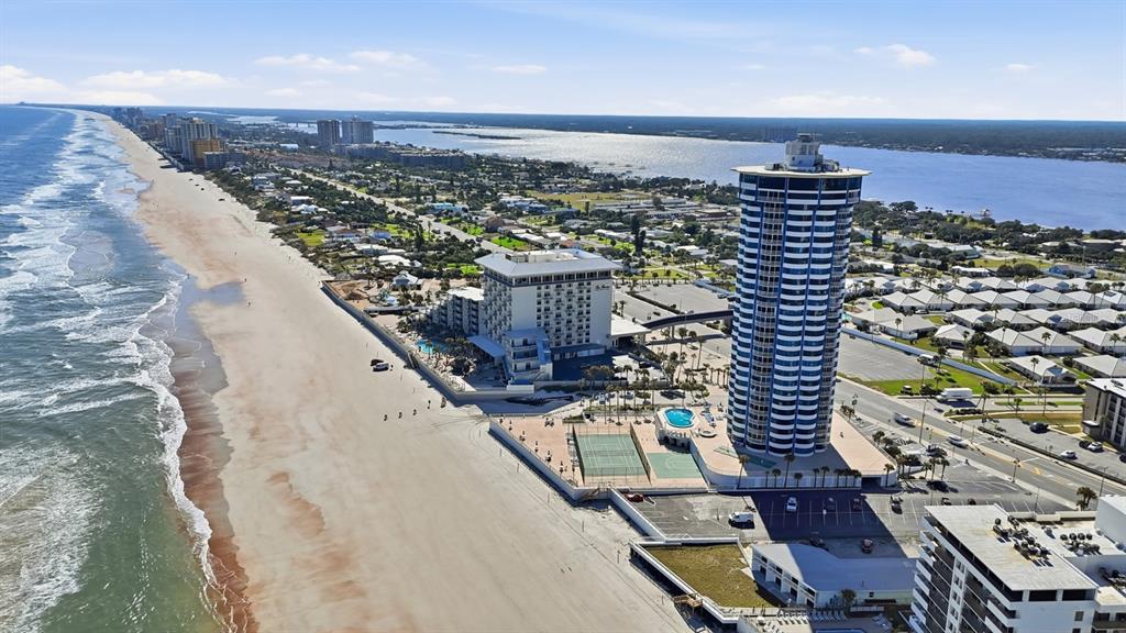 Aerial view of a beachside resort featuring a tall cylindrical tower and adjacent hotel building — 2625 S ATLANTIC AVENUE UNIT 18NW, DAYTONA BEACH, FL