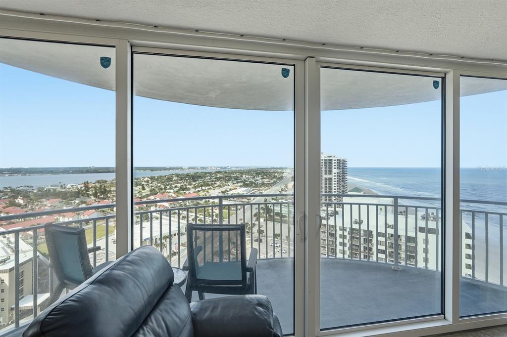 A living room features a leather sofa facing a balcony with ocean and bay views — 2625 S ATLANTIC AVENUE UNIT 18NW, DAYTONA BEACH, FL