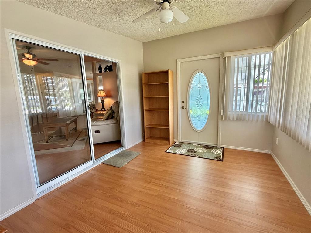 A sunroom with wood-look flooring, a sliding glass door, a bookshelf, and an exterior door — 303 HAWTHORNE BOULEVARD, LEESBURG, FL