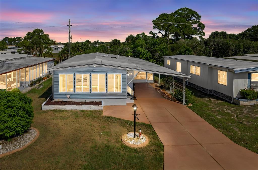 An exterior view of a light blue mobile home with a carport and concrete driveway — 240 LA COSTA, NORTH PORT, FL