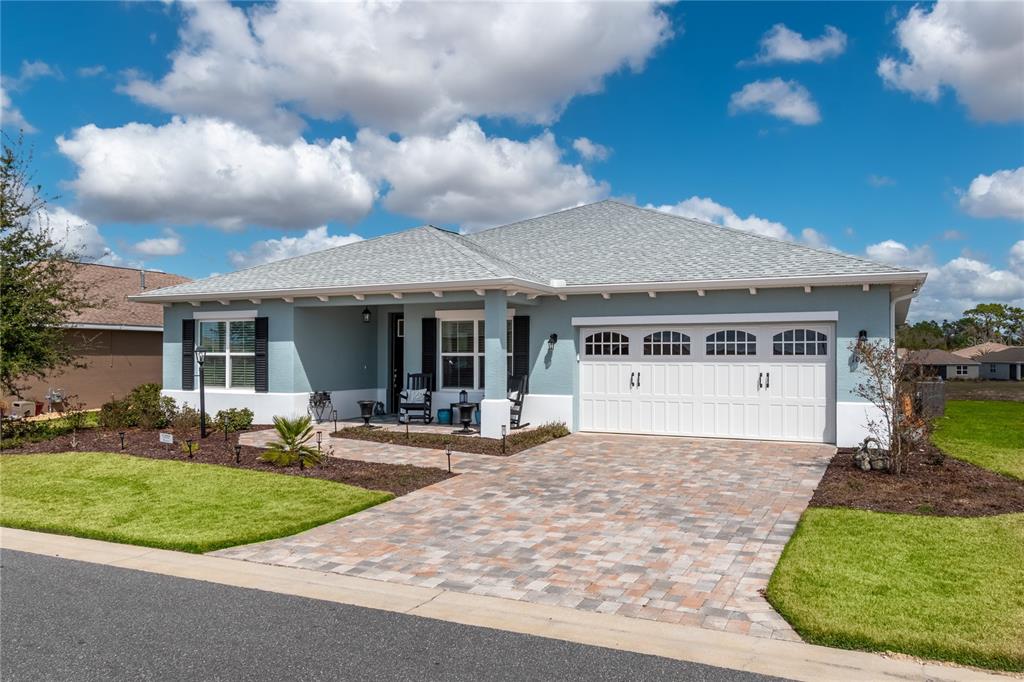 A light blue single-story house with a white trim, paver driveway, and a two-car garage — 10307 SW 96TH LANE, OCALA, FL