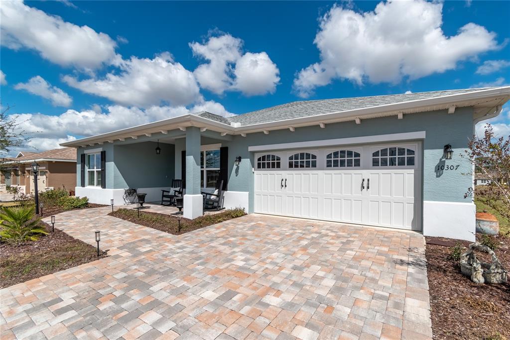 A light blue single-story house features a white garage door and a paved driveway — 10307 SW 96TH LANE, OCALA, FL